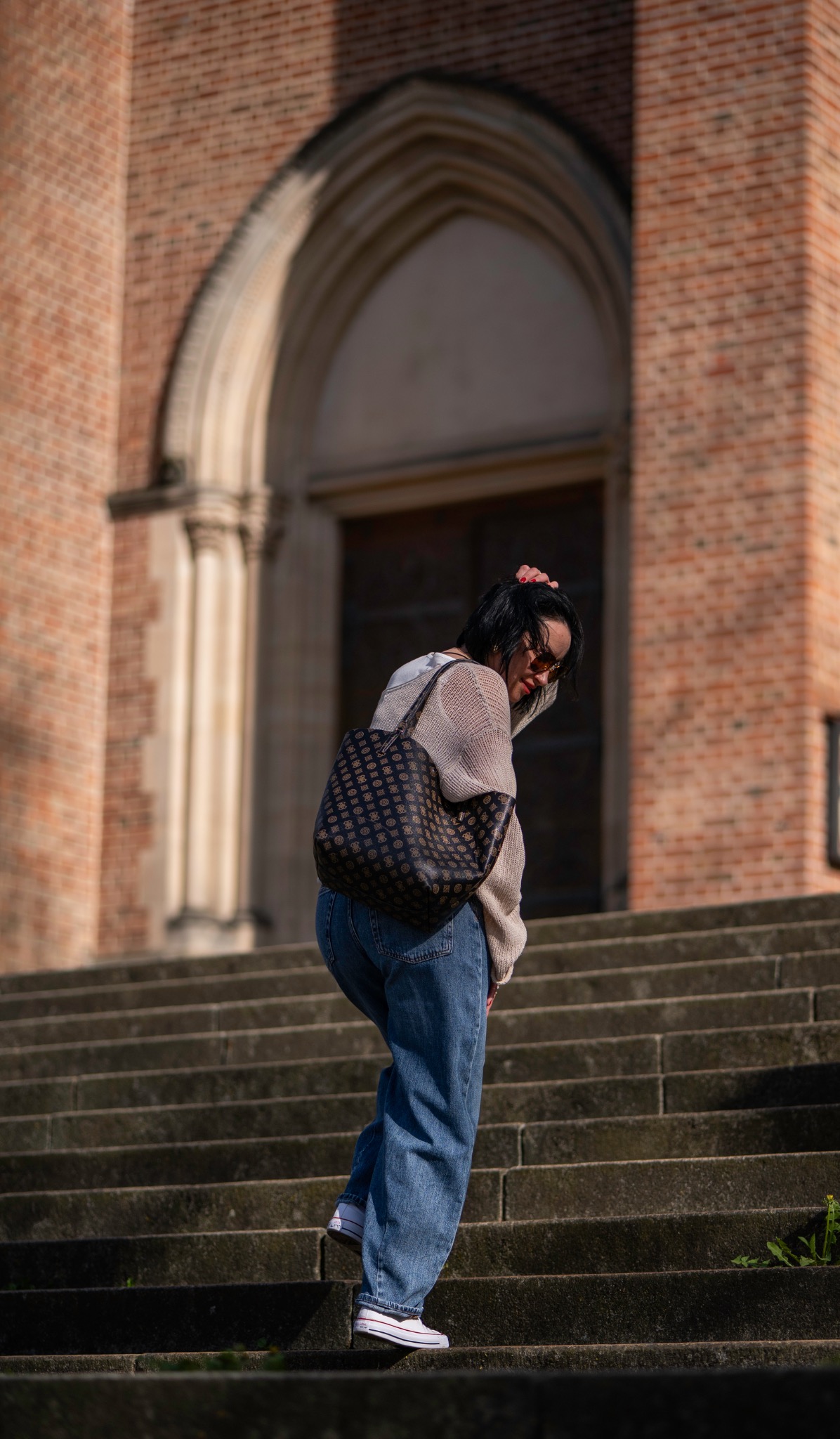 Woman on steps in front of a brick facade