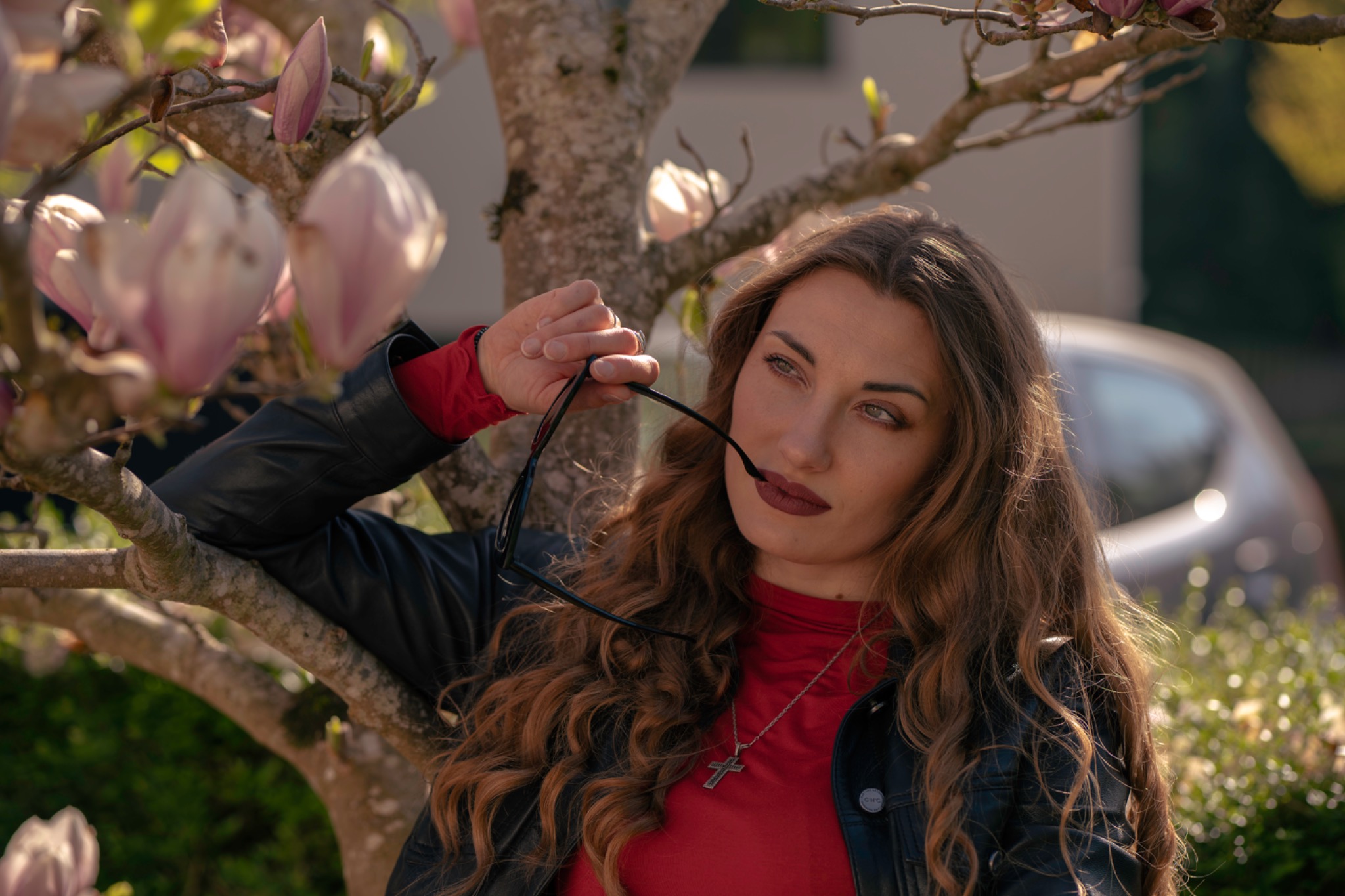 Woman in red and a leather jacket beneath blooming magnolia