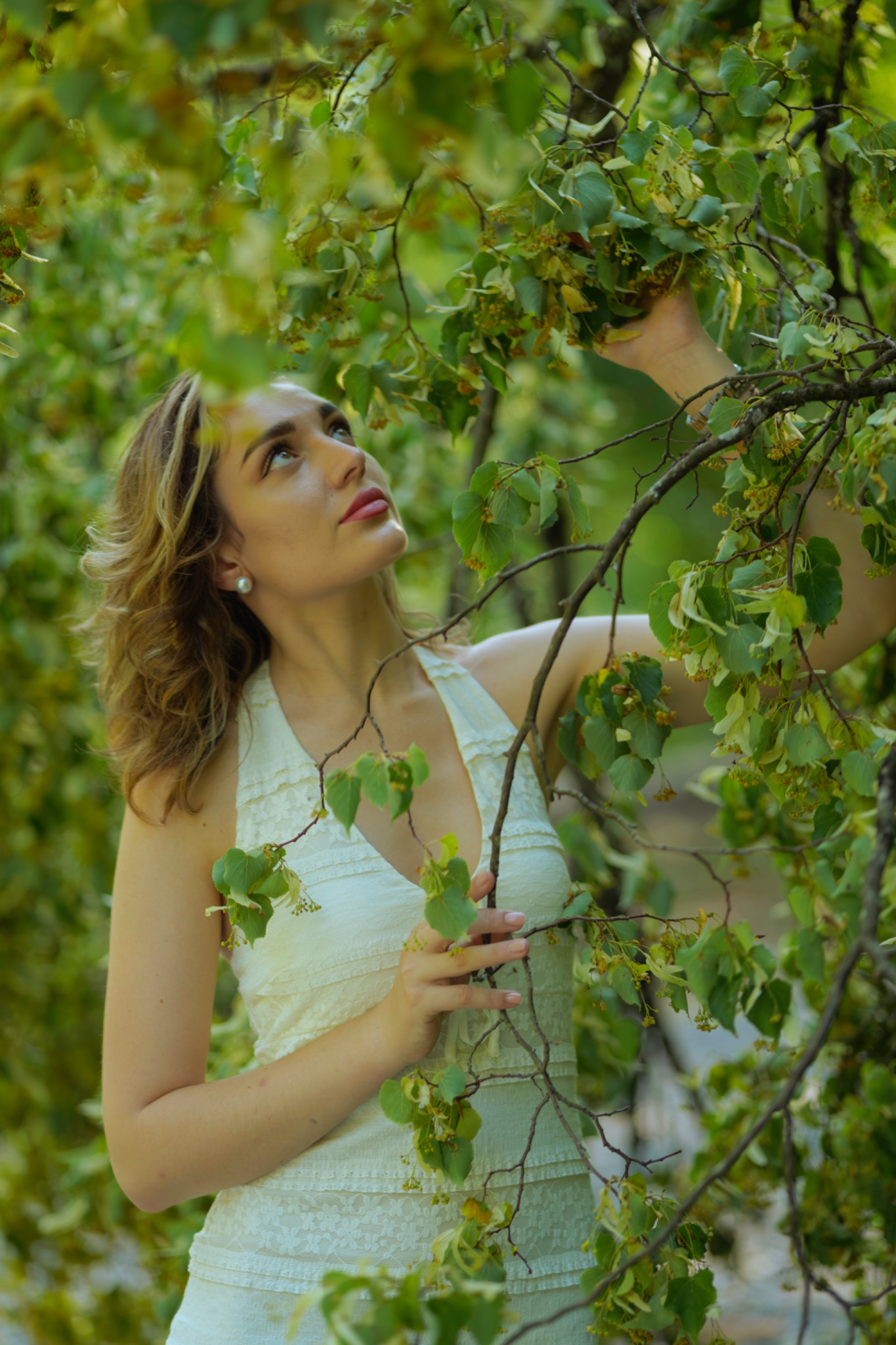 Woman in a white dress among green leaves